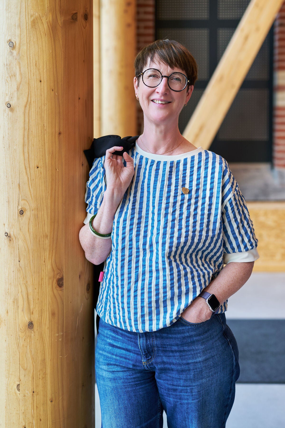 Blouse bleu et blanche veste dans la main appuyé contre colonne