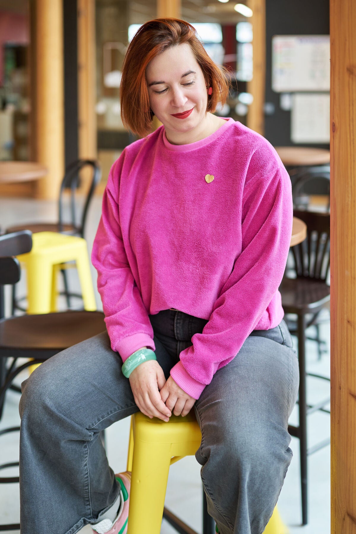 Sweat Fushia assise sur tabouret jaune
